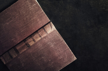 Photo of old antique opened book laying on leather table surface.