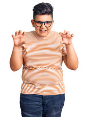 Little boy kid wearing casual clothes and glasses smiling funny doing claw gesture as cat,...
