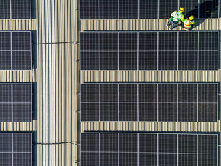 top aerial of engineer men inspects construction of solar cell panel or photovoltaic cell at roof top. Industrial Renewable energy of green power. factory at urban area. worker working on tower roof.