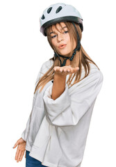 Teenager caucasian girl wearing bike helmet looking at the camera blowing a kiss with hand on air being lovely and sexy. love expression.