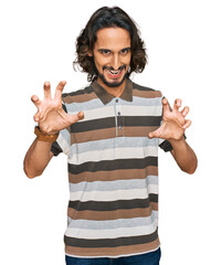 Young hispanic man wearing casual clothes smiling funny doing claw gesture as cat, aggressive and...