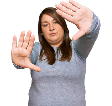Beautiful brunette plus size woman wearing casual clothes doing frame using hands palms and fingers, camera perspective