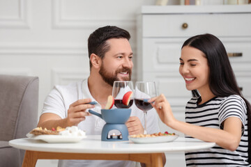 Obraz na płótnie Canvas Affectionate couple enjoying fondue during romantic date at home