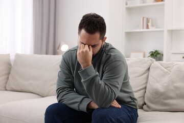 Fototapeta premium Man suffering from headache on sofa at home