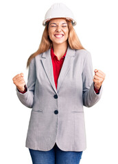 Beautiful young woman wearing architect hardhat excited for success with arms raised and eyes closed celebrating victory smiling. winner concept.