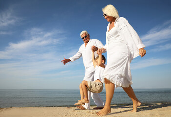 Cute little boy with grandparents spending time together on sea beach
