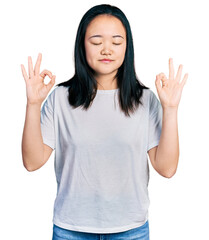 Young chinese woman wearing casual white t shirt relax and smiling with eyes closed doing meditation gesture with fingers. yoga concept.