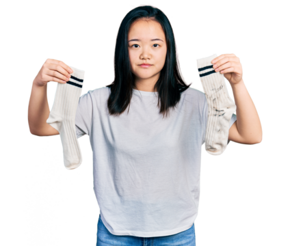 Young chinese woman holding socks relaxed with serious expression on face. simple and natural looking at the camera.