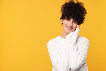 Happy young woman in stylish white sweater on yellow background, space for text