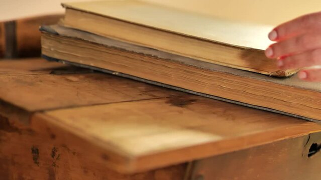 Old shabby books stack.Rare valuable books. Hands take books from a wooden table.Reading and education concept. 4k footage
