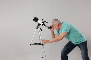 Senior astronomer with telescope on grey background