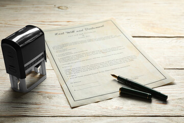 Last Will and Testament with stamp and pen on white wooden table