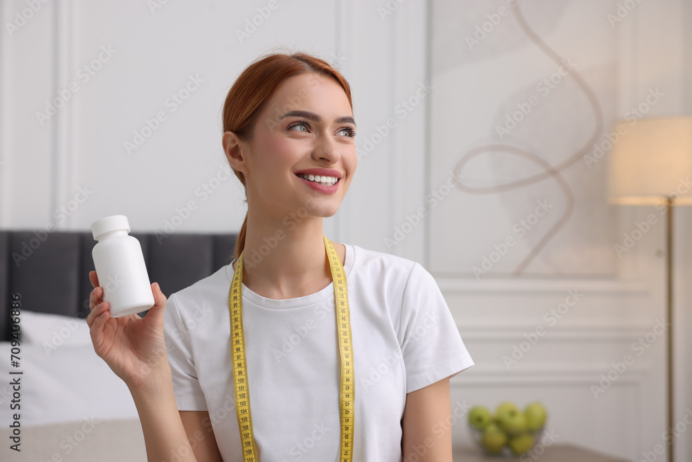 Sticker happy young woman with bottle of pills and measuring tape at home, space for text. weight loss