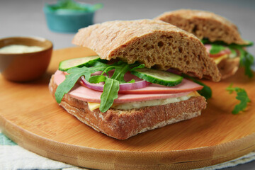 Tasty sandwiches with boiled sausage, cucumber and arugula on table, closeup © New Africa