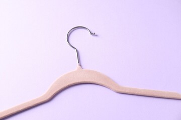 One beige hanger on violet background, top view