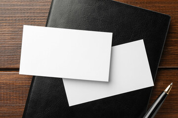 Blank business cards, notebook and pen on wooden table, flat lay. Mockup for design