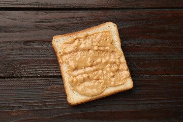 Delicious toast with peanut butter on wooden table, top view