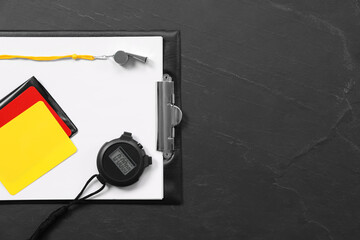 Referee equipment. Whistle, clipboard, cards and stopwatch on black table, top view with space for...