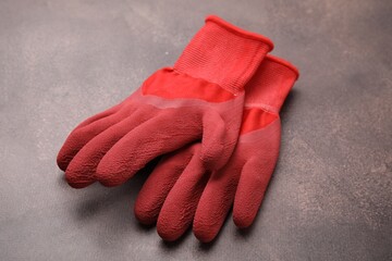 Pair of red gardening gloves on brown textured table