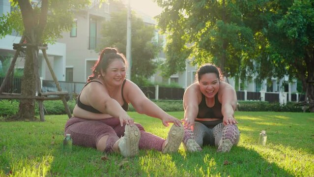 Obese two young asian woman doing stretching leg in the park, woman with overweight warm up and exercise for dieting and health, workout and motivation, oversized and challenge, plus size.