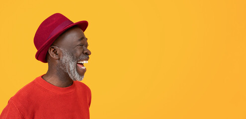 Side profile of a joyful black senior man laughing, dressed in a casual red sweater