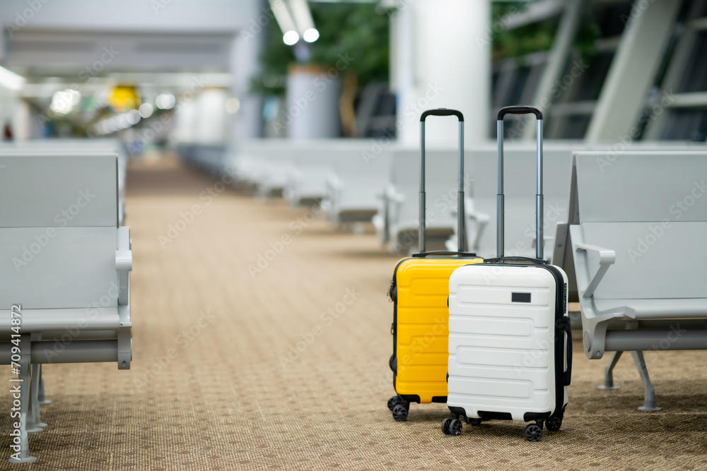 Wall mural Two suitcases in an empty airport hall, traveler cases in the departure airport terminal waiting for the area, vacation concept, blank space for text message or design