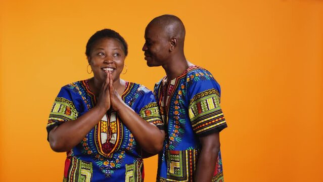 Ethnic man leaning in and telling secret to girlfriend on camera, giving away important confidential information and keeping privacy or secrecy. African american couple having fun with gossips.