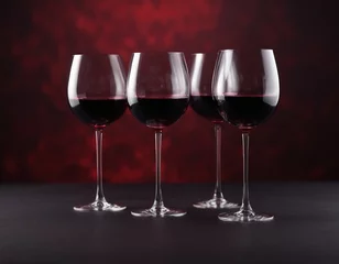 Fotobehang Red wine in a glass on a dark red and black background. Three glasses for wine. A romantic drink for a party, liquor store or wine tasting. Copy space © Pink Zebra