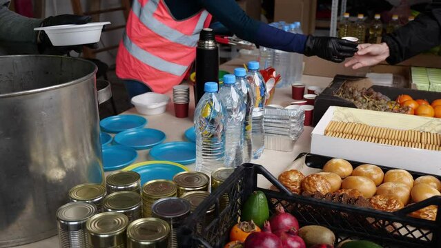 Volunteers in Humanitarian Aid Center, Handing Out Free Food for Local Community in Need. Team of Charity Workers Work at a Local Food Bank