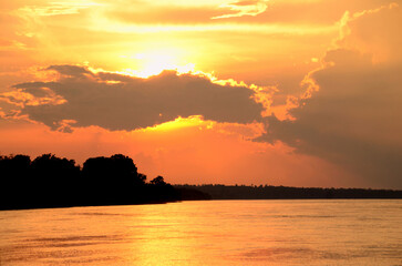 Naklejka premium Silhouette tranquil season wilderness serene landscape. Tranquil lake countryside sunrise seaside reflection. Tropical amazing dramatic golden sky on sunset over scenic river lake seascape ocean.