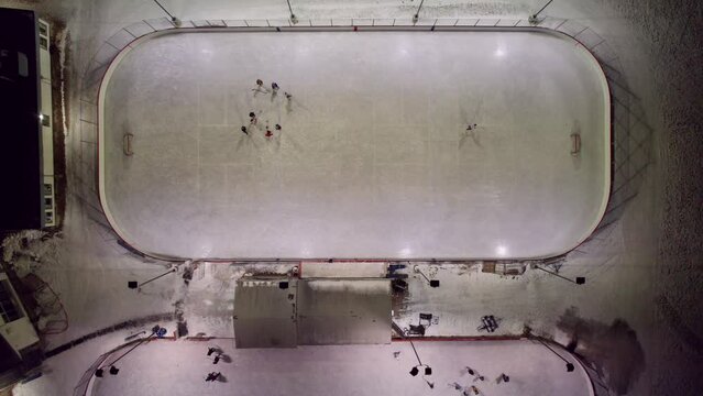 Overhead view of outdoor hockey rinks at night, 4K. Community centre in Winnipeg, MB with skaters and hockey players.