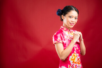 Portrait of an attractive Asian Chinese female wearing cheongsam or qipao on red background for Chinese New Year concept