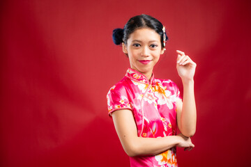 Portrait of an attractive Asian Chinese female wearing cheongsam or qipao on red background for Chinese New Year concept