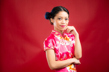 Portrait of an attractive Asian Chinese female wearing cheongsam or qipao on red background for Chinese New Year concept