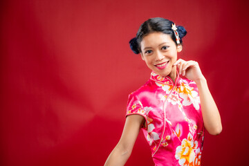 Portrait of an attractive Asian Chinese female wearing cheongsam or qipao on red background for Chinese New Year concept