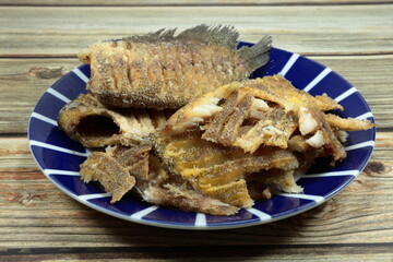 Pile of deep fried gourami fish (Snake skin fish) serving on the plate. Famous appetizer seafood menu in Asian restaurant. 
