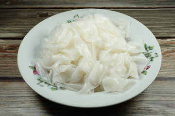 Chinese steamed dumplings. Pile of fresh and organic rice noodle on the plate. Famous carbohydrate ingredient in Asian kitchen.