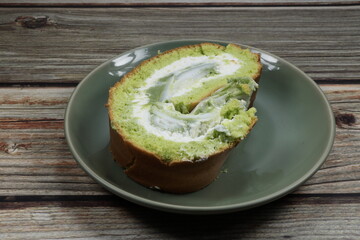 Sliced Traditional green Pandan Yamroll with soft cream serving on the plate. Famous sweet dessert in bakery shop.