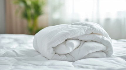 Fototapeta na wymiar White folded duvet lying on white bed background.