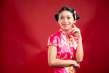 Portrait of an attractive Asian Chinese female wearing cheongsam or qipao on red background for Chinese New Year concept