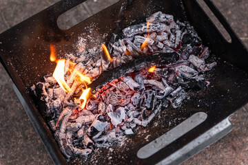 Close up of campfire, fire pit filled with burnt wood, flames. Fire burning, embers glowing.