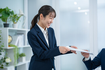 オフィスで書類を渡すスーツを着た女性
