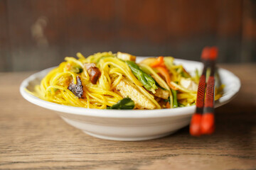 Stir fried Chinese vegetarian eggs noodle for Chinese vegetarian festival in ceramic plate on wooden background.