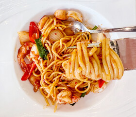Top view of Fork with just Spaghetti around on Fusion prawns and squids Stir Fried Chili Paste spaghetti in white ceramic plate.