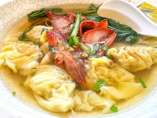 Closeup Chinese food Dumplings in pork bone soup with roasted red pork in white ceramic bowl.