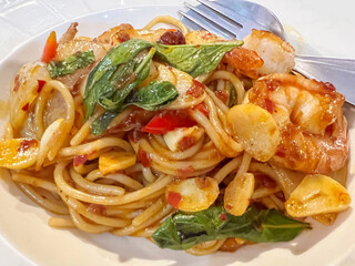 Closeup fusion prawns and squids Stir Fried Chili Paste spaghetti in white ceramic plate.