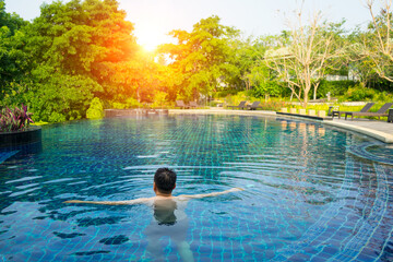 Man tourist to take a bath in the swimming pool near the forest park , sunlight with blue tiles and...