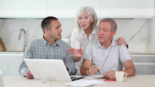 Couple of elderly man and woman while discussing deal with male salesman in kitchen