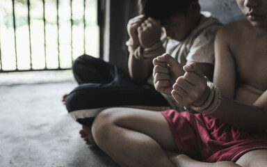 Victim boy with hands tied up with rope in emotional stress and pain,  restricted,   Stop violence against children and trafficking Concept. - obrazy, fototapety, plakaty