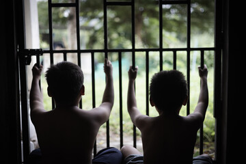 Children who were imprisoned in a room with a steel cage. The concept of stopping violence against children and human trafficking. - obrazy, fototapety, plakaty